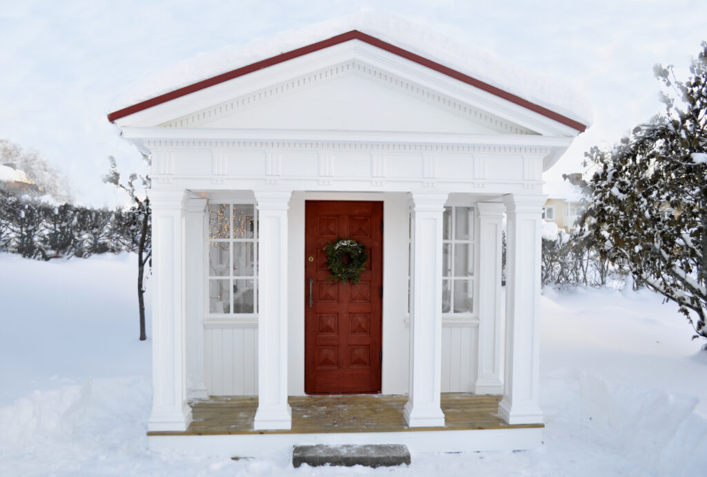 Front of roman-doric garden temple with handmade old-fashioned front door with mirrors.
